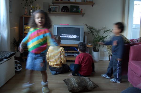 Olivia dances while Louis and Sam play videogames.